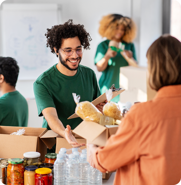 Volunteer handing a food donation box to a community member during a charity drive.