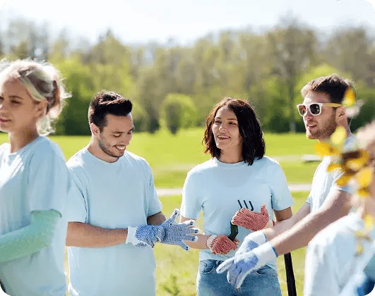 Volunteers in light blue shirts smiling and preparing for a park cleanup.
