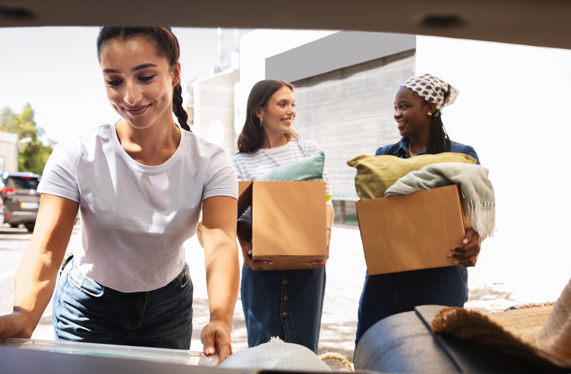 three-women-load-boxes-in-car-trunk-outside-2026-01-08-23-08-16-utc