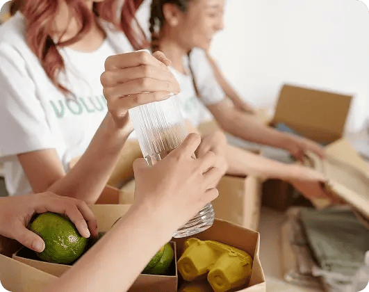 Volunteers packing food and household essentials into donation boxes.