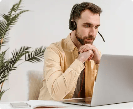 Professional man wearing a headset and looking at a laptop, representing customer support.